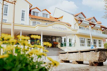 Hotel Dirsch in Titting Eingangsbereich des Hotels Dirsch mit Stufen und gelben Blumen im Vordergrund bei Tageslicht.